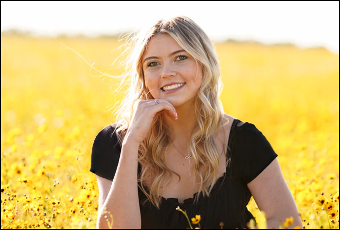 Smiling blonde woman in a yellow field.