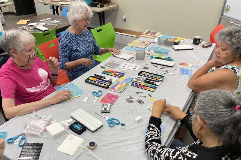 Four women sitting at a table crafting cards.