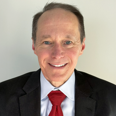 photo of Smiling man in a black suit with a red tie.