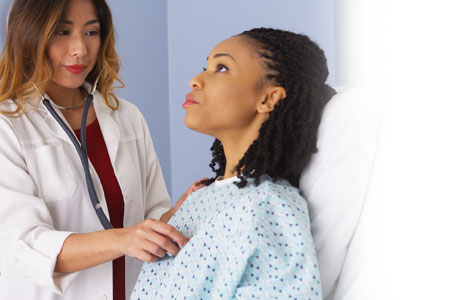 Photo of female doctor checking heart of female patient