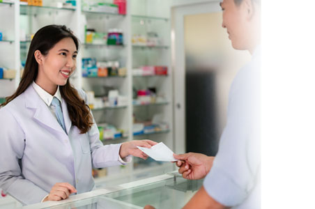 Photo of female pharmacist handing prescription to customer at counter