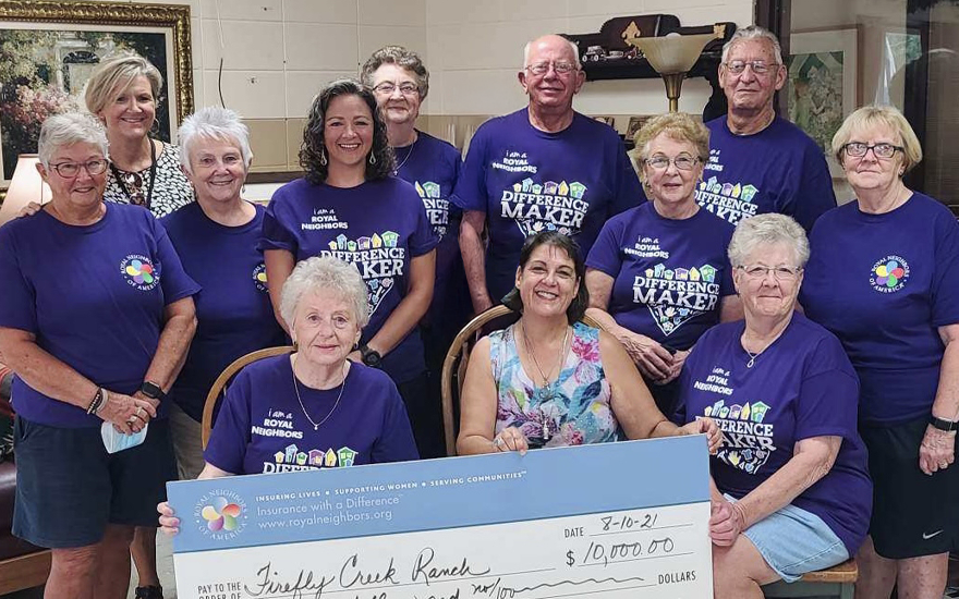 Group of happy people in purple t-shirts holding a giant $10,000 check.