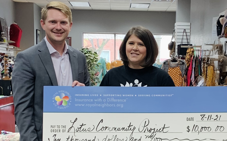 A happy man and woman holding a giant $10,000 check inside of a thrift store.