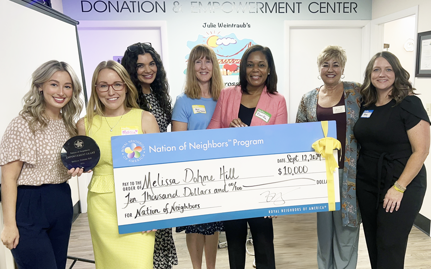Large group of happy women holding a giant $10,000 check.