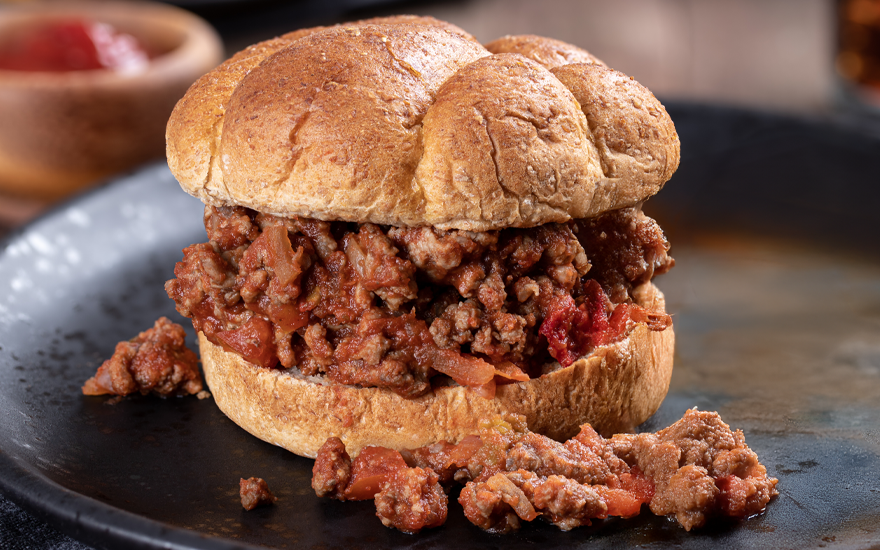 Close up of a Turkey Sloppy Joe on a wheat bun, on a black plate.