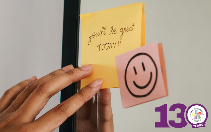 Close up of hand on yellow sticky note that says "You'll be great TODAY!" and a pink sticky note with a smiley face on it, both notes on a mirror.