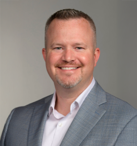 Smiling man in a gray suit.