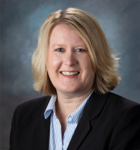 Smiling blonde woman with a black suit coat.