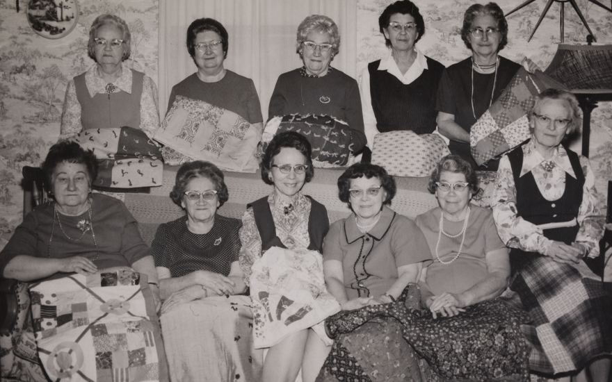 Black and white photo of Crothersville, Ind. chapter members in 1973 displaying their lap quilts designed for wheelchair users