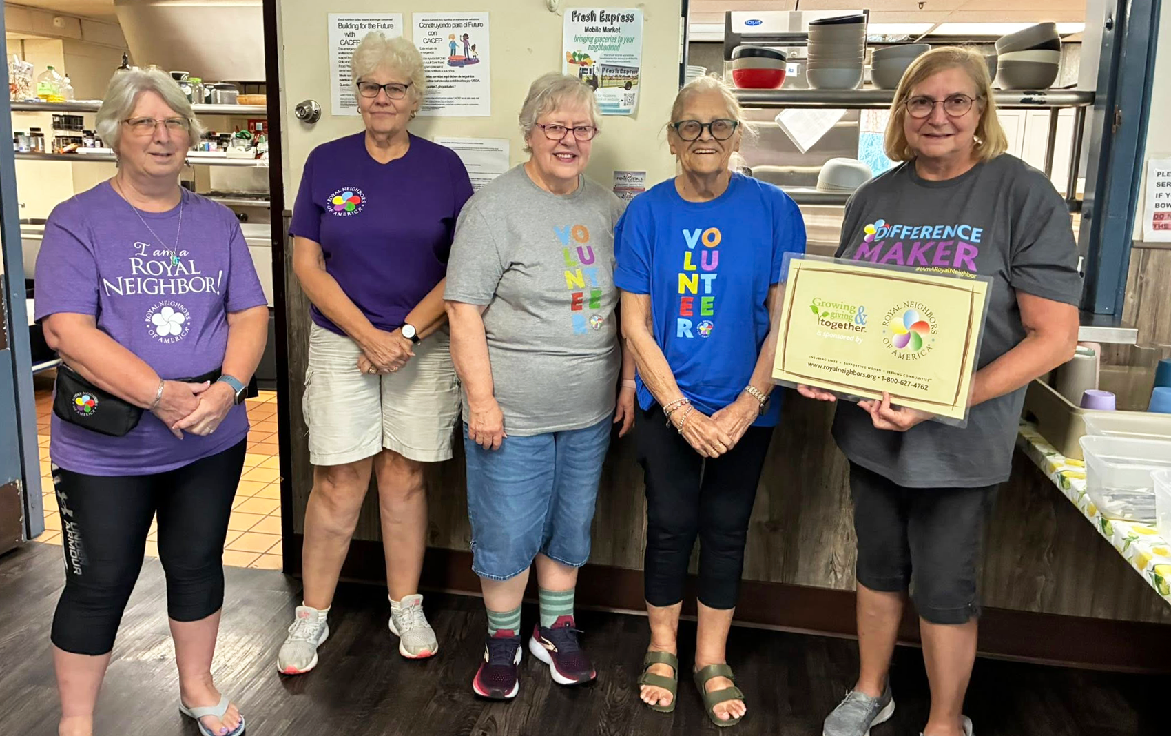 Group of five happy women with Royal Neighbors shirts in a kitchen.