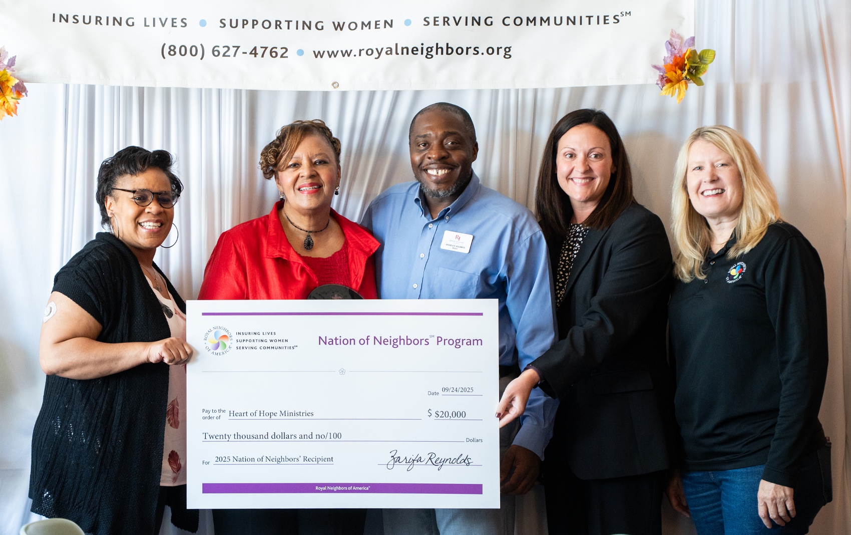 Smiling people holding a large $20,000 Nation of Neighbors check.