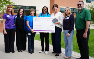 Group of happy people outside with a giant check and award.