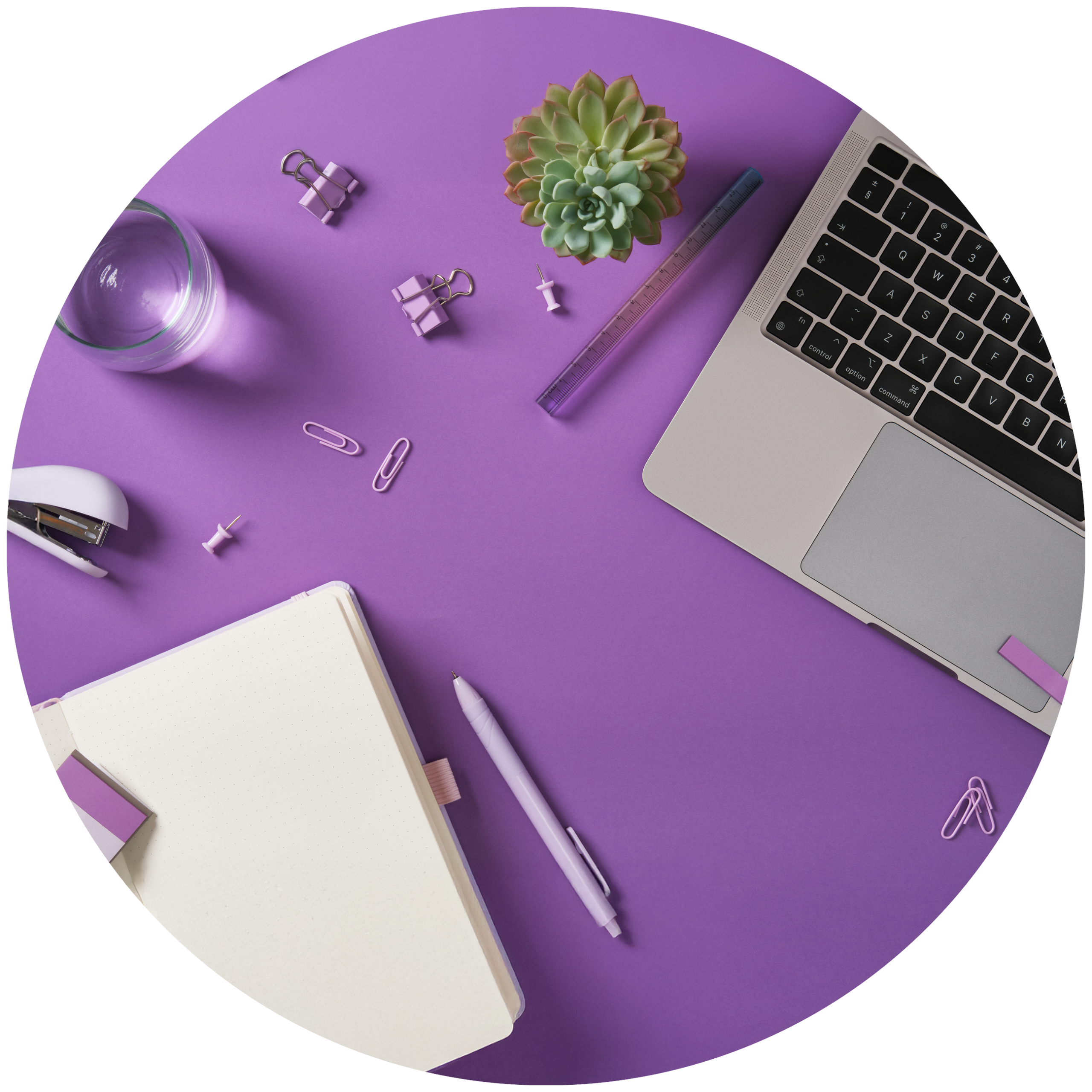 Partial view of a laptop, notebook, and other desk items on a purple desktop.
