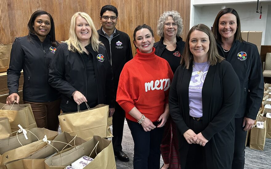 Happy smiling diverse group with brown paper bags filled at a volunteer activity.
