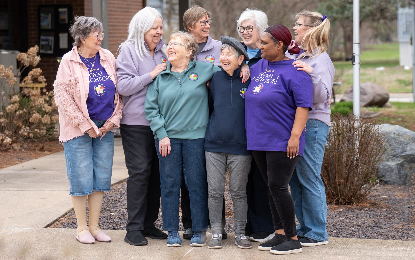 Group of eight happy women in a group smiling outside.