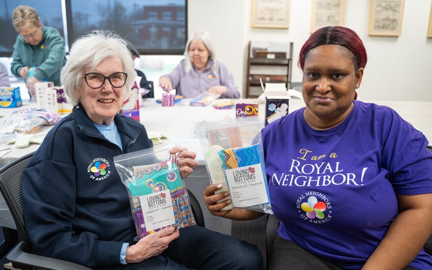 Group of happy women in Royal Neighbors attire making care kits.