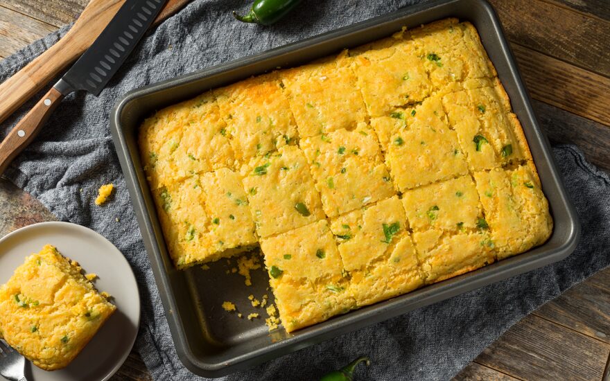 Cornbread with green chiles in a pan on a wooden table.